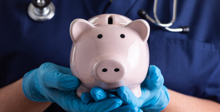 Doctor or Nurse Wearing Surgical Gloves Holding Piggy Bank. pedro braggio consultor financeiro clinicas medicas scaled