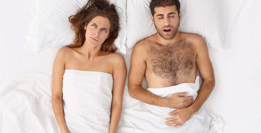 Stressful exhausted wife annoyed with husband snoring, has sleepless night, bored expression, poses in comfortable bed. Couple in bedroom sleep long during weekend. Top view. Problems with sleep Casal com vida sexual abalada, devido a crise financeira e dívidas