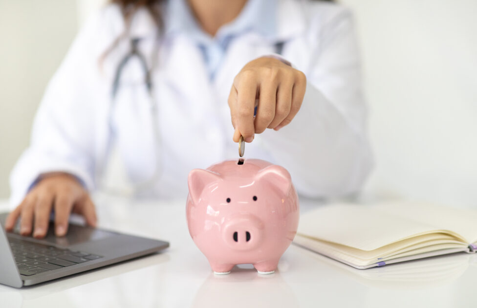 Médico guardando dinheiro no cofrinho após consultoria financeira para médicos